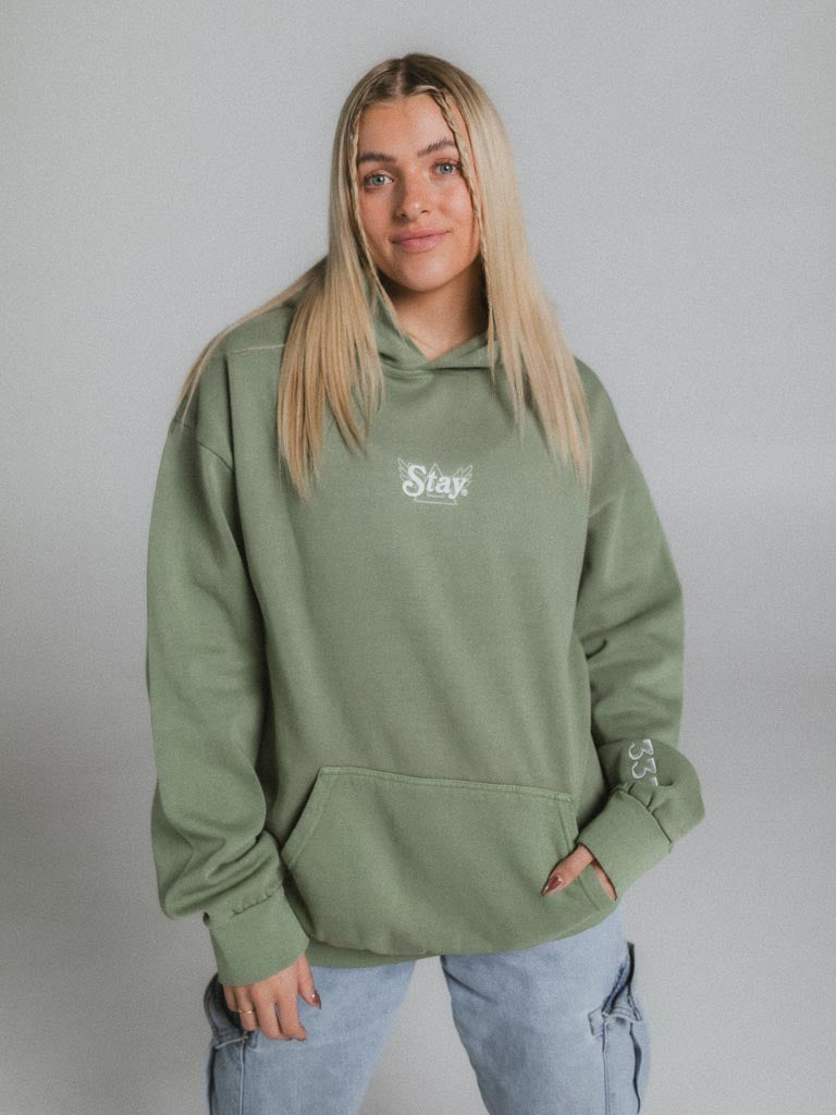 A woman in a green hoodie poses for a picture