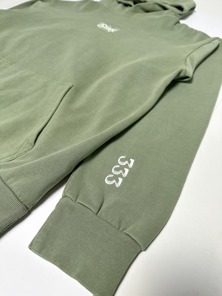 A close up of a green sweatshirt on a white surface